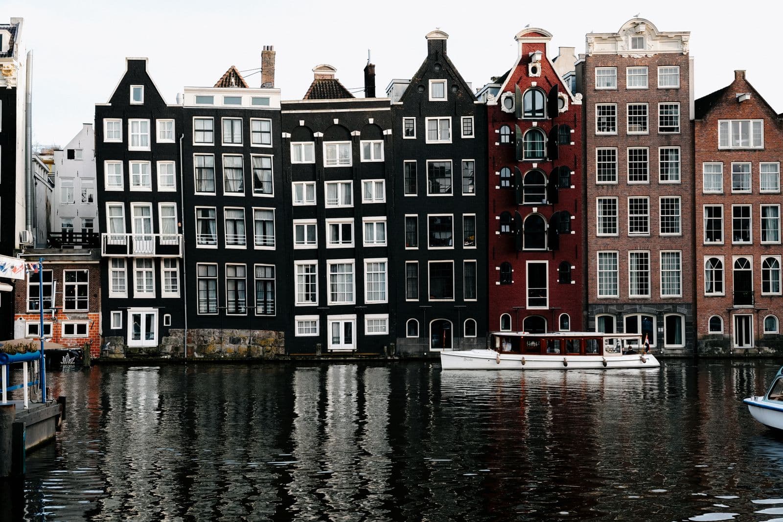 Stunning view of Amsterdam's iconic canal houses reflecting on water, showcasing unique architecture.